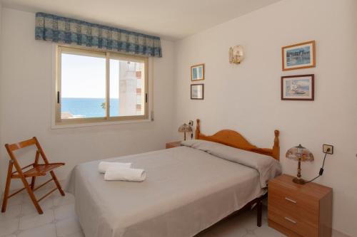 a bedroom with a bed and a window and a chair at Rentalmar Nabila in Miami Platja