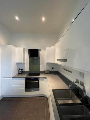 a kitchen with white cabinets and a sink at Stylish 1BD Flat - 1 Min from Bethnal Green in London