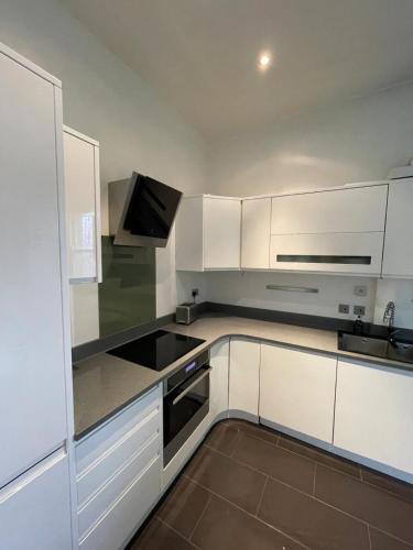 a white kitchen with white cabinets and a sink at Stylish 1BD Flat - 1 Min from Bethnal Green in London