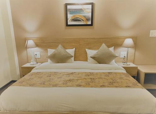 a bedroom with a large white bed with two lamps at Starlit Suites Shirdi in Nighoj