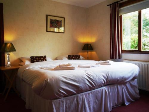 a bedroom with a large white bed and a window at Collin Hill House in Castle Douglas