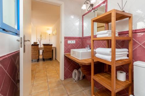 ein Badezimmer mit einem Waschbecken und einem Regal mit Handtüchern in der Unterkunft Mas Tinus - Palmera in Santa Cristina d'Aro