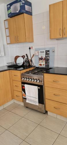 a kitchen with a stainless steel stove and wooden cabinets at Eagles nest III Furnished apartments in Nairobi