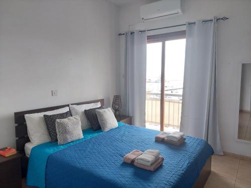 a bedroom with a blue bed with towels on it at Penthouse with roof garden in Zygi village Marina in Larnaca