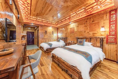 two beds in a room with wooden walls at Baike Boutique Hotel in Longsheng