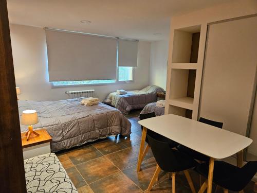a bedroom with a bed and a desk and a table at Del Cerro Departamentos x 4 in El Calafate