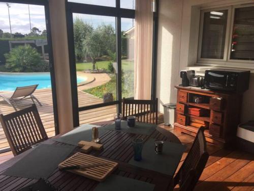 ein Esszimmer mit einem Tisch und Poolblick in der Unterkunft Aux portes de Bordeaux, chambre indépendante in Cénac