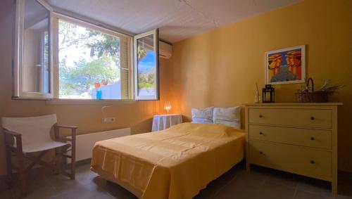 ein Schlafzimmer mit einem Bett mit einer Kommode und einem Fenster in der Unterkunft Villa with swimming pool and tennis/basketball court in Theológos