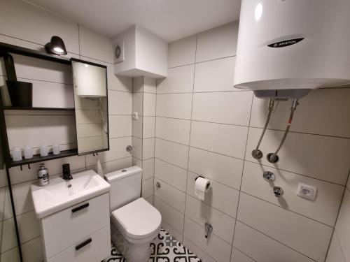 ein Badezimmer mit einem WC, einem Waschbecken und einem Spiegel in der Unterkunft Bowler Hat Apartment Belgrade in Zvezdara