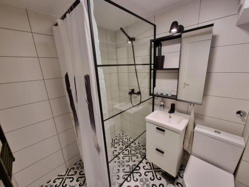 a white bathroom with a sink and a shower at Bowler Hat Apartment Belgrade in Zvezdara