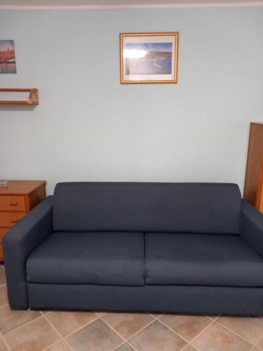 Sofá azul en una habitación con una foto en la pared en Residence Sole Dell'Argentario, en Porto Santo Stefano