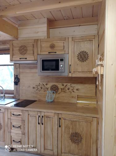 a kitchen with wooden cabinets and a microwave at Pokoje ,,Goramiba''Jurgów in Jurgów