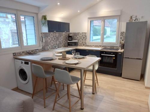 une cuisine avec une table, des chaises et un réfrigérateur dans l'établissement Cottage neuf - Forêt de Tronçais, à Urçay