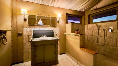 a bathroom with a sink and a shower at Twyfelfontein Adventure Camp in Khorixas