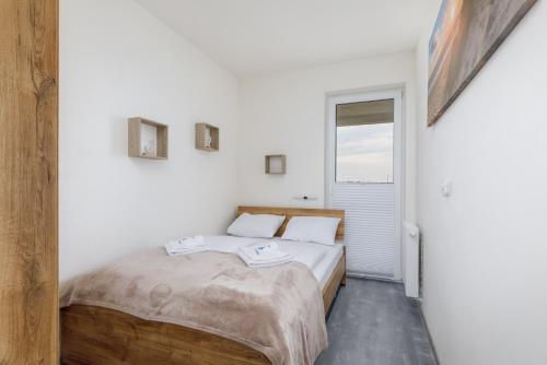 een slaapkamer met een bed met witte muren en een raam bij Sea Resort Nowa Flotylla Świnoujście by Renters in Świnoujście