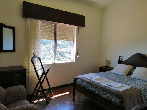1 dormitorio con cama, ventana y silla en Vista Boa, en Porto da Cruz