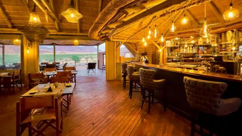 a restaurant with a bar and tables and chairs at Twyfelfontein Adventure Camp in Khorixas