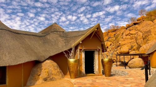a small building with a black roof and two vases at Twyfelfontein Adventure Camp in Khorixas