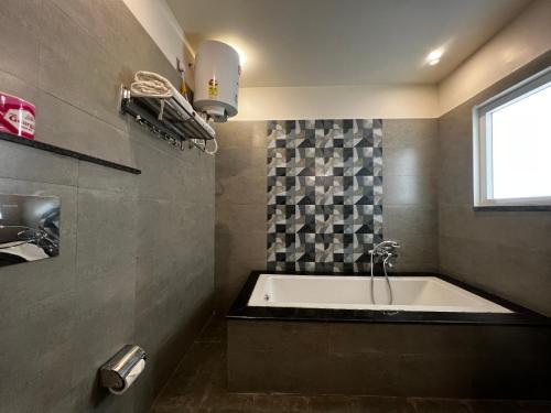 a bathroom with a bath tub and a window at HOTEL JS SOUVENIR in Dehradun