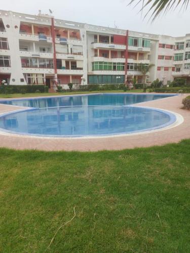 a large swimming pool in front of a large building at Appartement avec piscine proche de la plage in Mohammedia