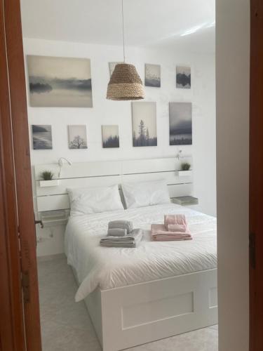 una camera da letto con un letto bianco e quadri appesi al muro di Casa sul mare a Torre Canne