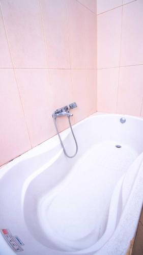 a bath tub in a bathroom with pink tiles at Villa Violet 2 Private Pool by Masterpiece Villa in Batu