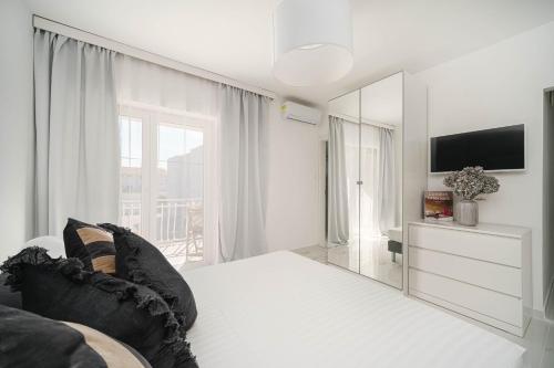 a white living room with a mirror and a tv at Apartments and Room Anka in Vodice