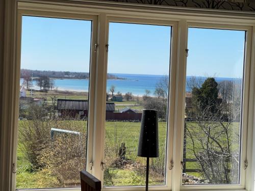 a window with a view of a field and water at Klinta sea view in Köpingsvik