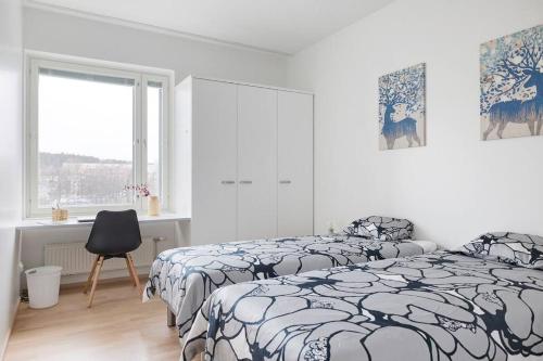 a white bedroom with two beds and a chair at Rauhallinen kolmio omalla saunalla Tampereen keskustassa in Tampere