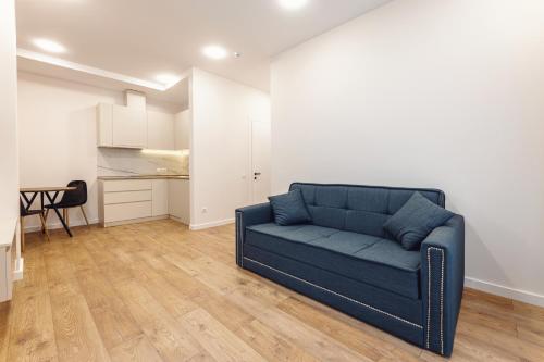 a living room with a blue couch and a kitchen at Next Green Aparthotel OFFICIAL in Batumi