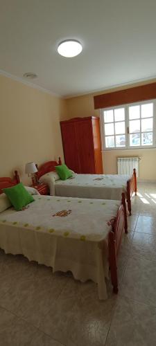 Zimmer mit 3 Betten und grünen Kissen in der Unterkunft EnBurela Lujo A Pie de Playa in Burela