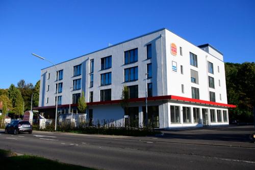 Smart & Stay Aparthotel Saarbrücken Süd - Self-Check-In - Free Parking في ساربروكن: مبنى ابيض على جانب شارع