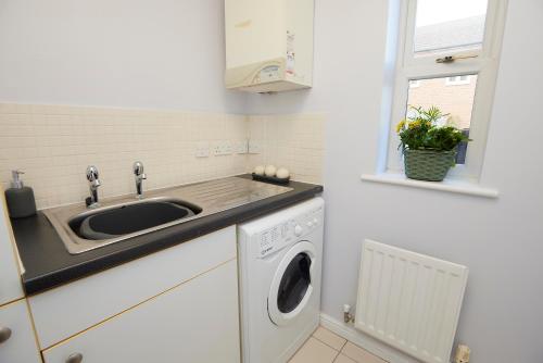 a kitchen with a sink and a washing machine at Evergreen House - Modern 4-bed Family, Contractors, Free Netflix, Fast WiFi, NEC, Resorts World, JLR, Airport in Solihull