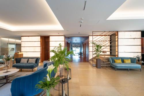 a lobby with blue couches and plants at Lasala Plaza Hotel - Adults Only in Donostia-San Sebastián