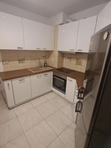a small kitchen with white cabinets and a refrigerator at Sweet Home & Sweet Cats & Fast internet in Wrocław