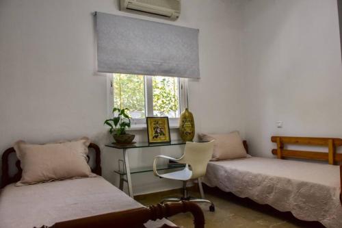 1 Schlafzimmer mit 2 Betten, einem Schreibtisch und einem Fenster in der Unterkunft Μονοκατοικία δίπλα στην Θάλασσα in Salamís
