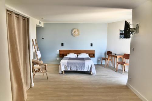 Un dormitorio con una cama y una mesa en una habitación. en hôtel Le Grand Large, en Gruissan
