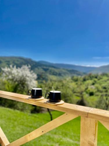 two black cups sitting on top of a wooden rail at Bali Glamping in Ambrolauri