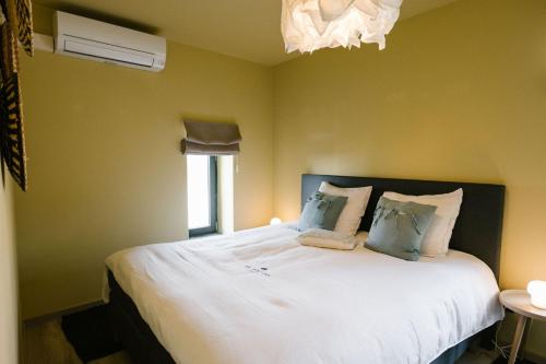 um quarto com uma grande cama branca com almofadas azuis em Hoeve de Reetjens - La Porcherie em Bilzen