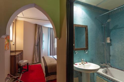 uma casa de banho com um lavatório, uma banheira e uma cama em Le Caspien Boutique Hotel em Marrakech