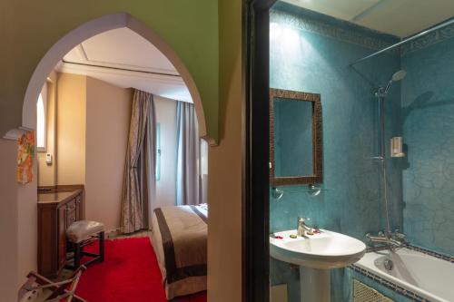Le Caspien Boutique Hotel في مراكش: حمام مع حوض وحوض وسرير