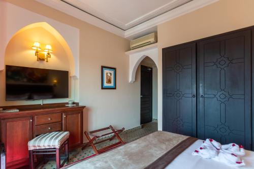 a bedroom with a bed and a dresser and a tv at Le Caspien Boutique Hotel in Marrakech