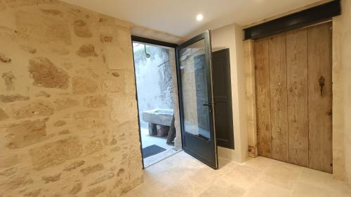 a bathroom with a glass door and a stone wall at Dastro Logis in Saint-Rémy-de-Provence