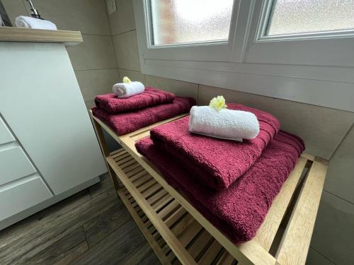 três toalhas numa prateleira de madeira na casa de banho em Maison des Sens em Saint-Omer