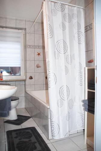 a bathroom with a shower curtain and a tub and a sink at Ferienwohnung Schmäing, Haiger/Westerwald / Rothaarsteig in Haiger