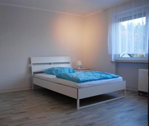a bedroom with a bed with blue sheets and a window at Ferienwohnung Schmäing, Haiger/Westerwald / Rothaarsteig in Haiger
