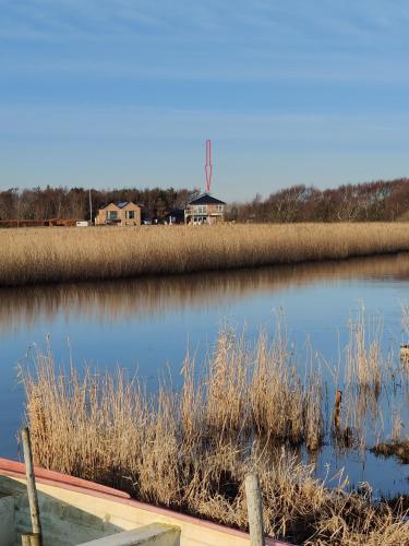 a body of water with a farm in the background at Villa-Amby in Ringkøbing
