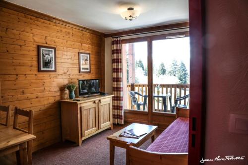a living room with a television and a balcony at travelski home premium - Résidence Les Alpages de Val Cenis 4 in Les Champs