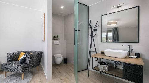 ein Badezimmer mit einem Waschbecken, einem Stuhl und einem Spiegel in der Unterkunft A stunning villa with a swimming pool in Lindar near Pazin in Lindar