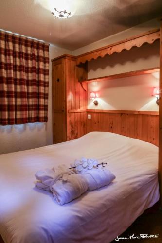 une chambre avec un lit blanc avec des fleurs dessus dans l'établissement travelski home premium - Résidence Les Alpages de Val Cenis, à Les Champs